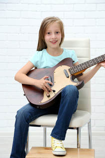 Providence Guitar Academy student holding her guitar and smiling at the camera. 