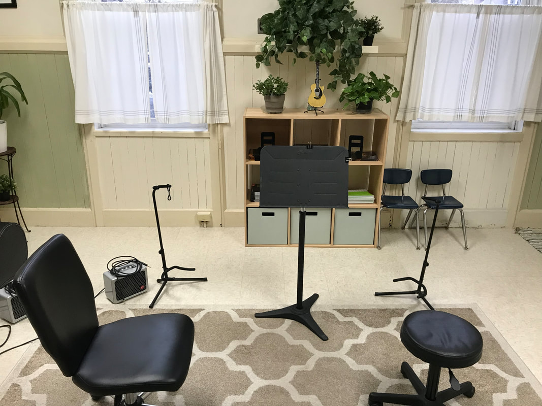 Guitar lessons room with amplifier, music books, and music stands.