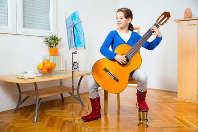 Young girl practicing classical guitar and reading music at her home in Providence, RI.